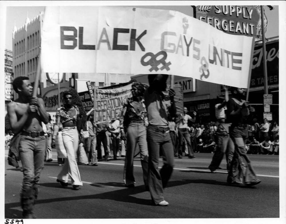 Pat Rocco, Men hold a "Black Gays Unite" banner at the Los Angeles Christopher Street West pride parade, 1975.  Coll2007-006 Pat Rocco photographs and papers, ONE Archives at the USC Libraries.